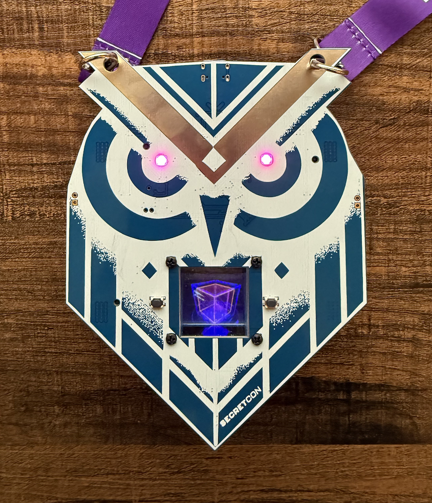 Picture of an owl-shaped blue PCB with a screen near the mouth area.